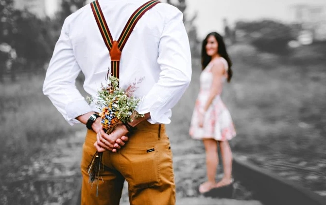 MarriageWeek, Liebespaar mit Mann, der einen Blumenstrauss hinter seinem Rücken versteckt